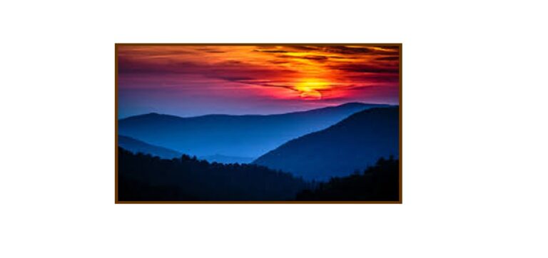Mountain sunset scene with orange skies and dark, blue mountains